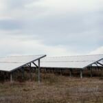 Imagem de painéis solares em um campo aberto sob céu nublado, destacando a geração de energia limpa e sustentável. Ideal para quem busca energia renovável.