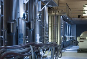 Imagem de uma instalação industrial com tanques de aço e equipamentos de processamento, ideal para indústrias de alimentos, bebidas ou produtos químicos.